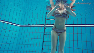 Busty and beautiful fresh redhead babe in the pool undresses underwater