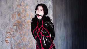 Babe in a latex bodysuit is bondaged, gagged and put on her knees